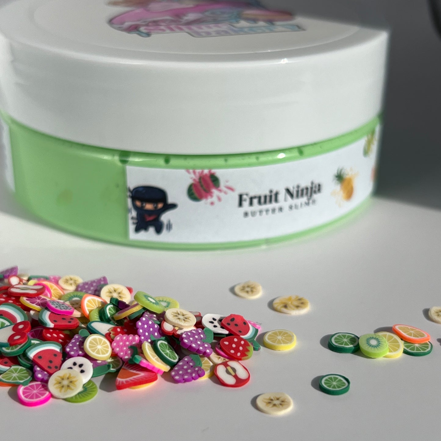 Glossy bright green butter slime with a smooth, pliable texture, decorated with multi-coloured fruit charms. Delivers a fruity scent and satisfying sensory play.