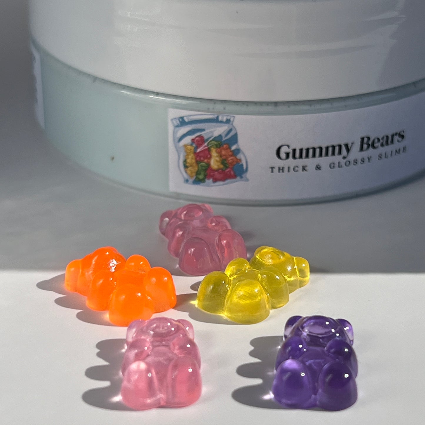 Shiny, thick light blue slime with a sleek, glossy feel, embellished with multi-coloured gummy bear acrylic charms. Perfect for sensory play and relaxation, with a sweet, playful scent.