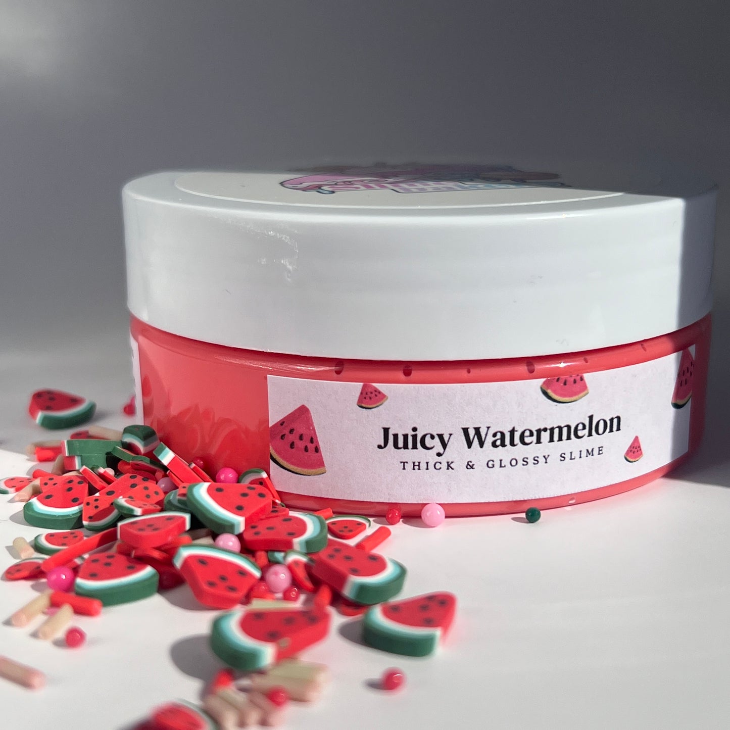 Juicy red butter slime with a soft, pliable texture, embellished with green watermelon slice polymer charms. Offers a refreshing watermelon scent, perfect for a satisfying sensory experience.