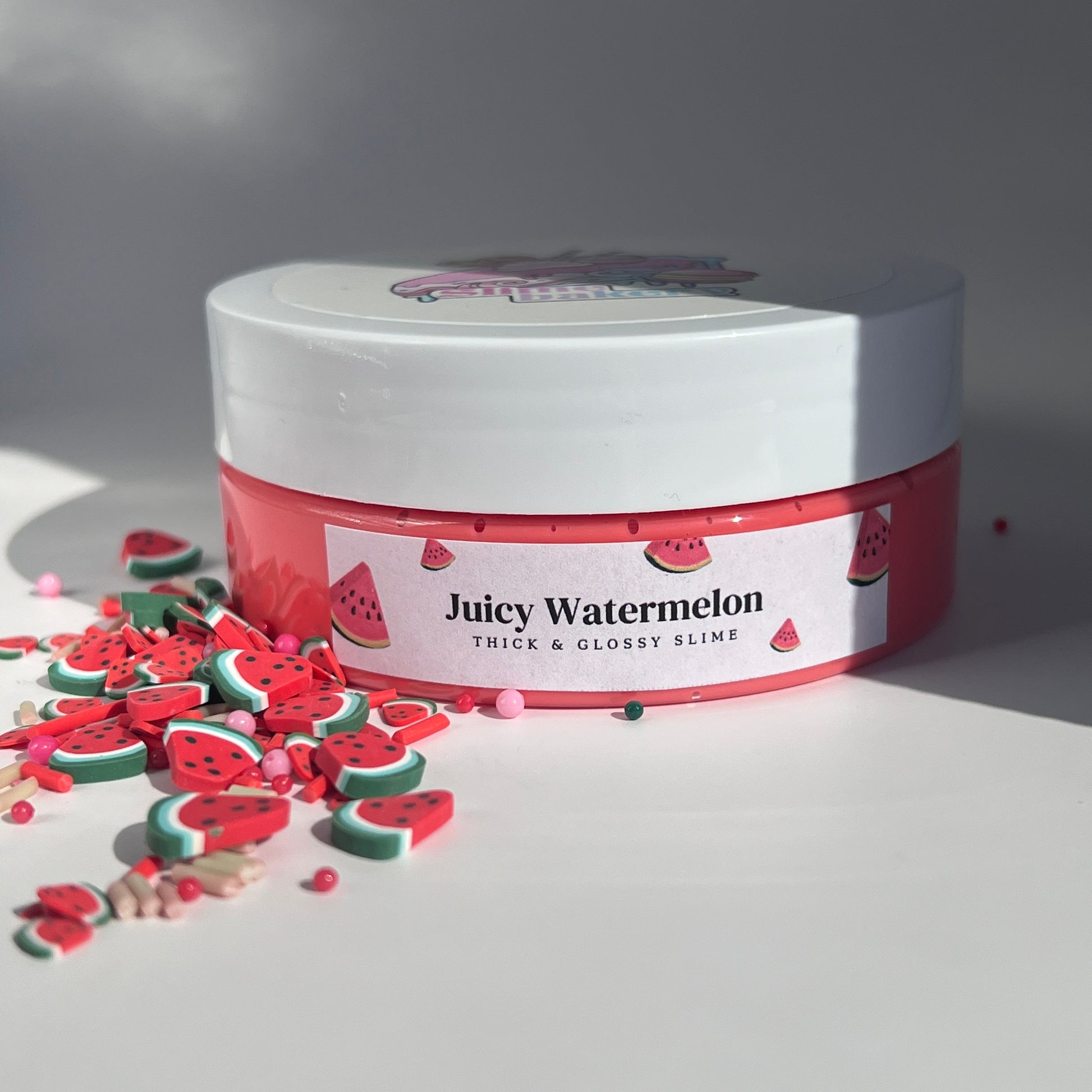 Vibrant watermelon red butter slime with a creamy, velvety feel, adorned with playful green watermelon slice charms. Scented like juicy watermelon, ideal for stress relief and fun.