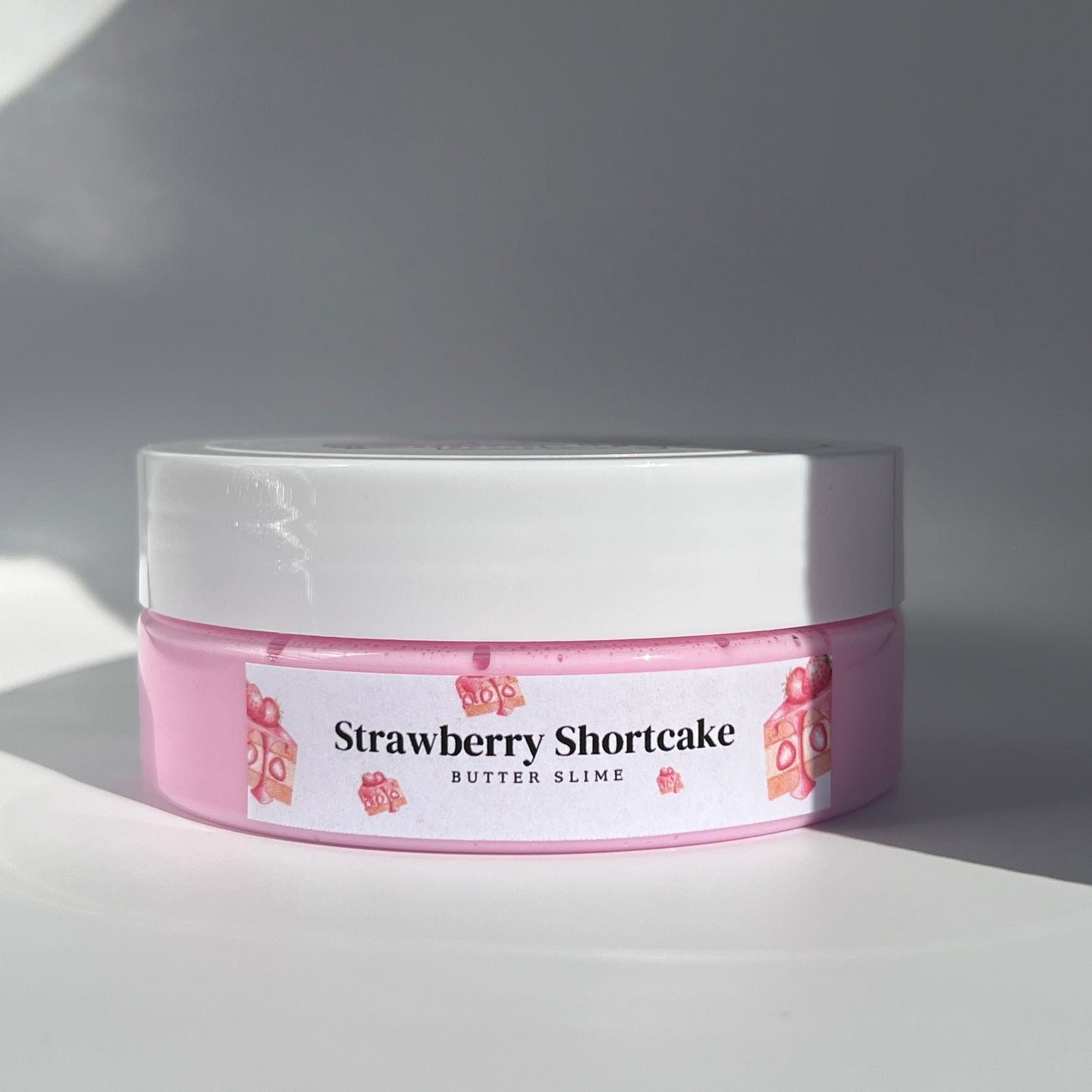 Soft pink butter slime with a creamy, velvety texture, featuring strawberry shortcake polymer charms. Infused with the sweet scent of strawberry shortcake, perfect for stretching, moulding, and sensory play.