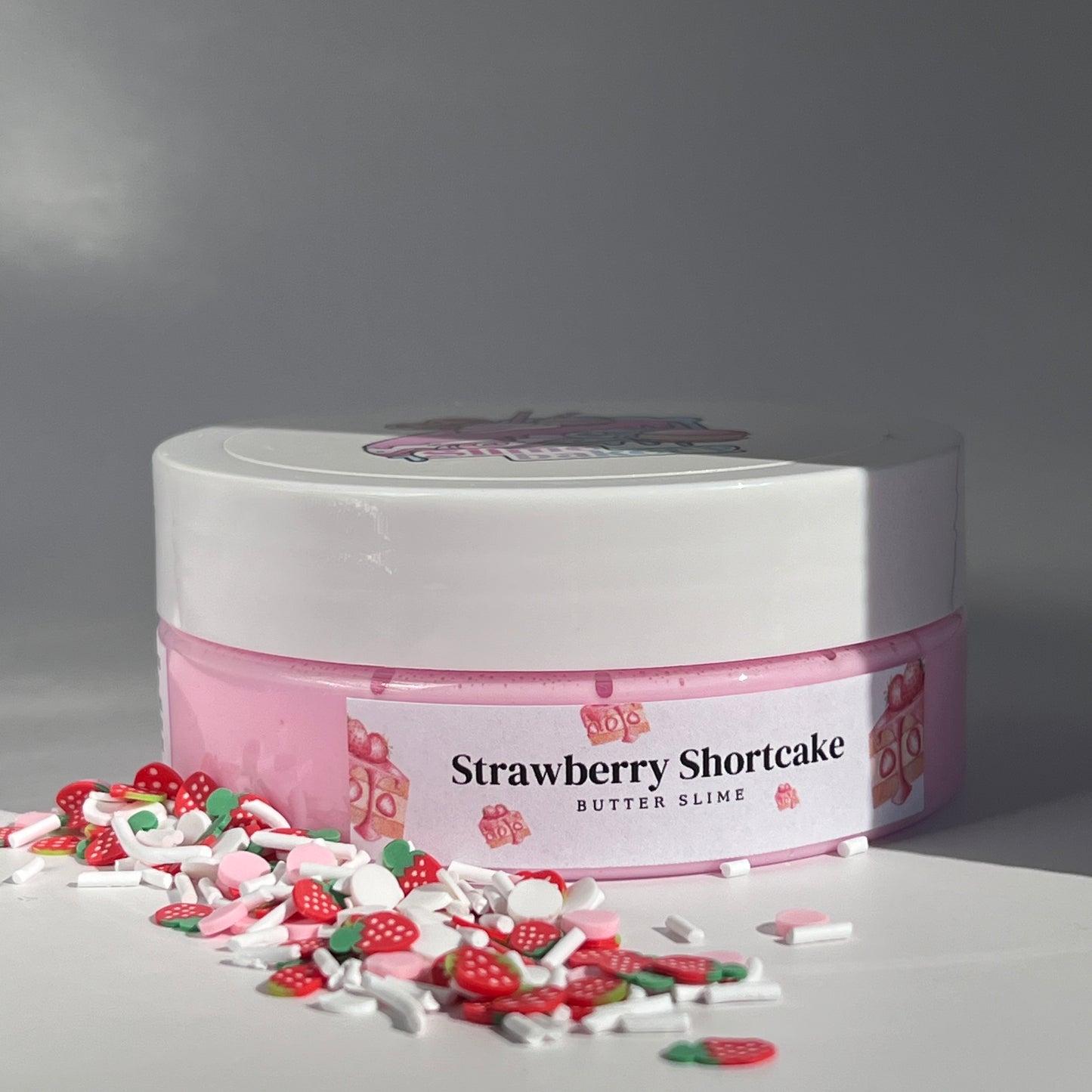 Lush pink butter slime with a smooth, spreadable texture, adorned with cute strawberry shortcake charms. Scented like freshly baked strawberry shortcake, ideal for sensory relaxation and creative play.